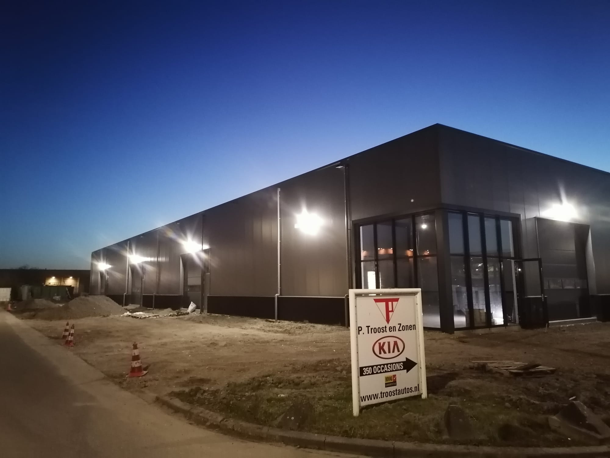 Nieuwe zwarte bedrijfshal in de schemering met brandende gevelverlichting