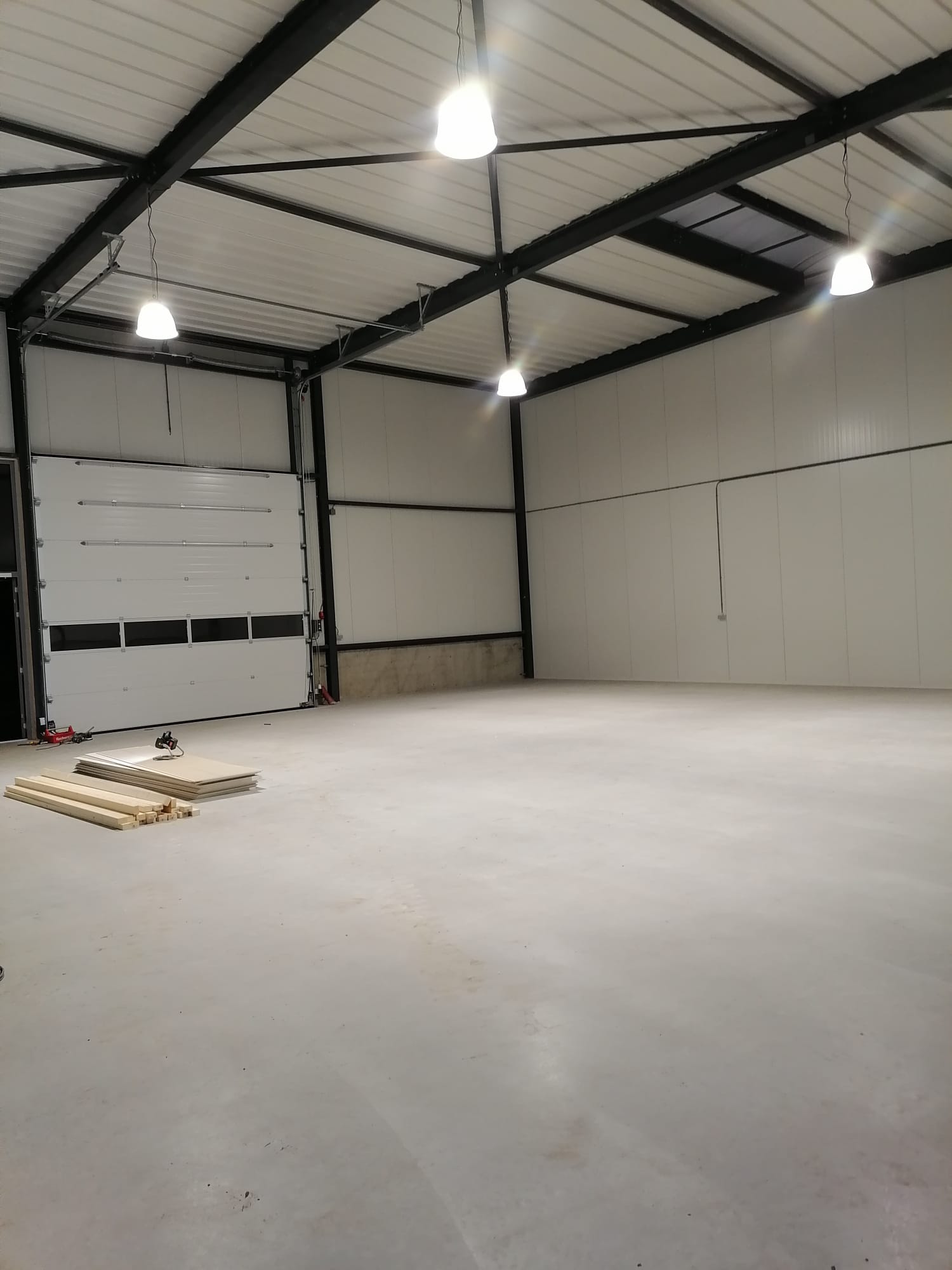 Interieur van een lege bedrijfshal met brandende hanglampen en een sectionaaldeur