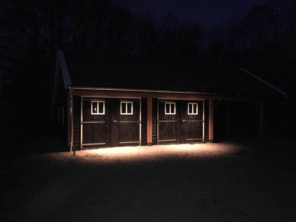 Dezelfde schuur ’s avonds, met de buitenverlichting aan